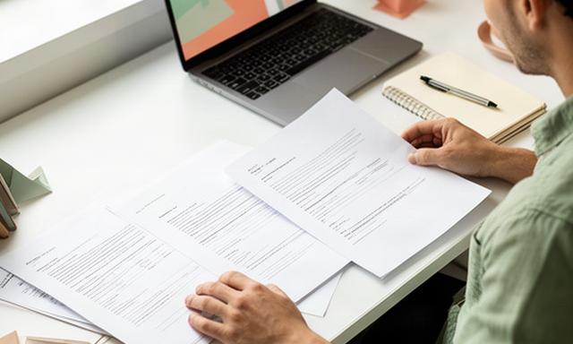 Profesional autónomo de diseño trabajando con contratos sobre una mesa luminosa